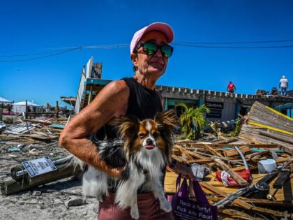 US-WEATHER-HURRICANE-IAN A resident holds her pet as she walks past debris on San Carlos Island in Fort Myers, Florida, in the aftermath of Hurricane Ian on October 1, 2022. - Shocked Florida communities counted their dead Saturday as the full scale of the devastation came into focus, two days after …
