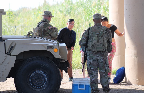 After safely crossing the Rio Grande near where dozens drowned in FY22, the migrant family is being held by Texas National Guards under Operation Lone Star.  (Randy Clark/Breitbart Texas)