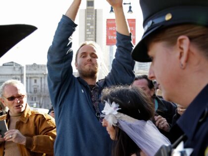 David DePape, center, records Gypsy Taub being led away by police after her nude wedding outside City Hall on Dec. 19, 2013, in San Francisco. DePape is accused of breaking into House Speaker Nancy Pelosi's California home and severely beating her husband with a hammer. DePape was known in Berkeley, …