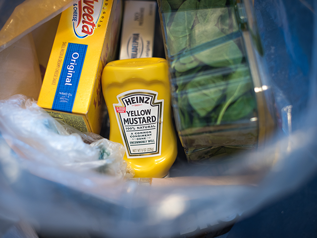 A bottle of Heinz Kraft Co. Heinz brand Yellow Mustard sits in a grocery bag in an arrange