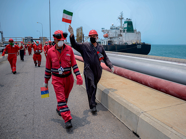 A worker of the Venezuelan state oil company PDVSA waves an Iranian flag as the Iranian-fl
