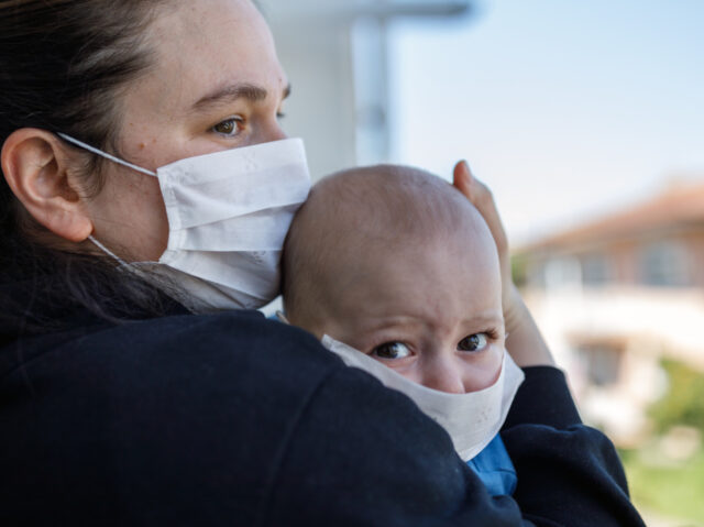 Portrait of Mother and baby boy covering face with pollution mask against COVID-19