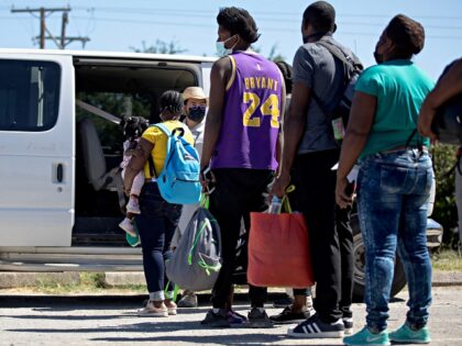 Haitian migrants who are seeking asylum wait to get into a van to be transported from Del