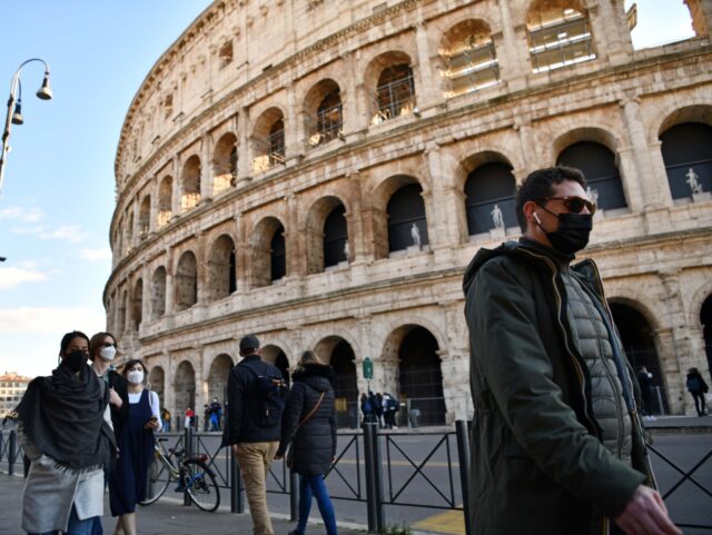People wearing face masks walk past the Colosseum in Rome, Italy, on Jan. 24, 2022. On Mon