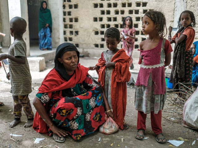 Medina Ahmed (2nd L), a displaced person from Konaba, sits next to children in a compound of abandoned buildings, where internally displaced people are sheltered, near the town of Dubti, 10 kilometers from Semera, Ethiopia, on June 7, 2022. - The Afar region, the only passageway for humanitarian convoys bound …
