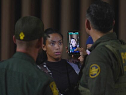 A US Border Patrol officer holds his smartphone and scans the face of a woman who illegally crossed the US-Mexico border in Yuma, Arizona in the early morning of July 11, 2022. - Every year, tens of thousands of migrants fleeing violence or poverty in Central and South America attempt …