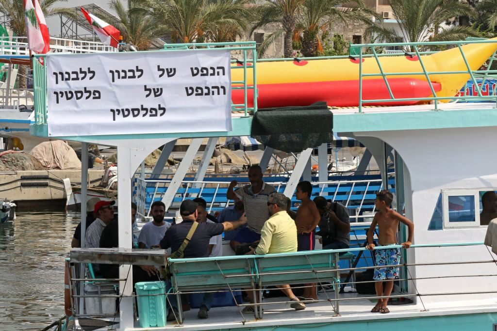 A sign reading in Hebrew "Lebanon's oil is for Lebanon and Palestine's oil is for Palestine" is displayed on a boat taking part in a Lebanese marine rally affirming the country's right to its offshore gas wealth, running from the southern coastal city of Tyre towards Naqoura near the maritime border with Israel on September 4, 2022. - The maritime border dispute between Lebanon and Israel escalated in early June, after Israel moved a production vessel to the Karish offshore field, which is partly claimed by Lebanon. The move prompted Beirut to call for the resumption of US-mediated negotiations on the demarcation dispute. (Photo by MAHMOUD ZAYYAT / AFP) (Photo by MAHMOUD ZAYYAT/AFP via Getty Images)