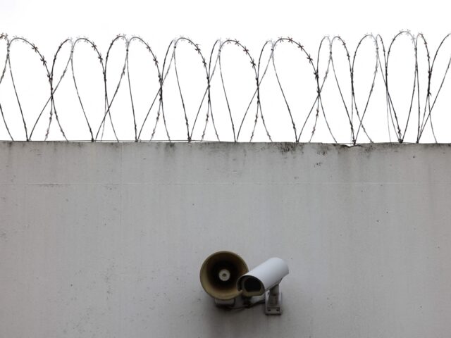 This photograph taken on September 7, 2022, shows barbed wires and a video-camera on a wal