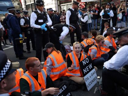 Protesters, some with their necks padlocked together, block the road as they take part in a demonstration by Just Stop Oil climate activists at Piccadilly Circus London on October 9, 2022. (Photo by ISABEL INFANTES / AFP) (Photo by ISABEL INFANTES/AFP via Getty Images)