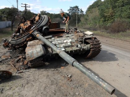 A girl inspects a destroyed Russian tank near the village of Oskol, Kharkiv region, on Oct