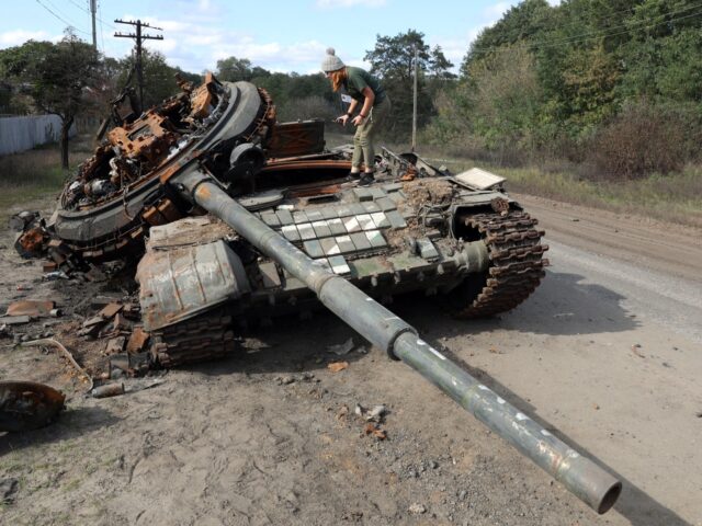 A girl inspects a destroyed Russian tank near the village of Oskol, Kharkiv region, on Oct