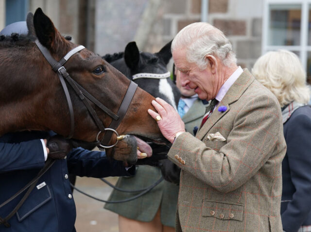 BALLATER, SCOTLAND - OCTOBER 11: King Charles III feeds carrots to horses as he attends a