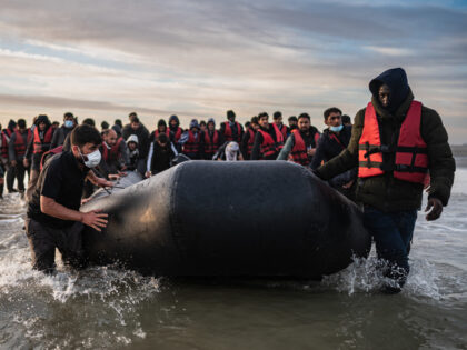 TOPSHOT - Migrants move a smuggling boat into the water as they embark on the beach of Gravelines, near Dunkirk, northern France on October 12, 2022, in an attempt to cross the English Channel. - Since the beginning of the year, more than 33,500 people have already made the perilous …
