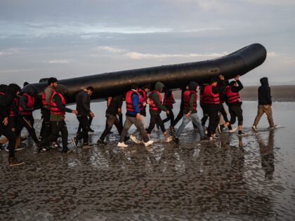 Migrants carry a smuggling boat on their shoulders as they prepare to embark on the beach