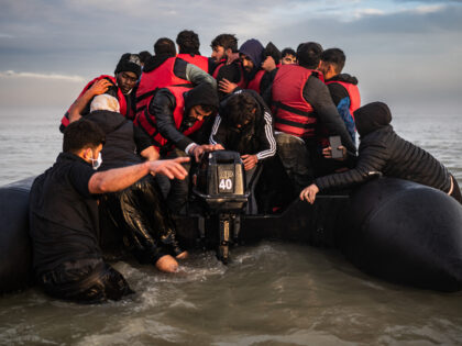 Migrants try to start an outboard engine after boarding a smuggler's boat on the beach of