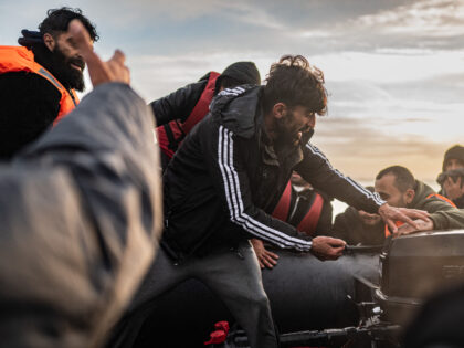 TOPSHOT - Migrants try to start an outboard engine on board a smuggler's boat on the beach of Gravelines, near Dunkirk, northern France on October 12, 2022, in an attempt to cross the English Channel. - Since the beginning of the year, more than 33,500 people have already made the …