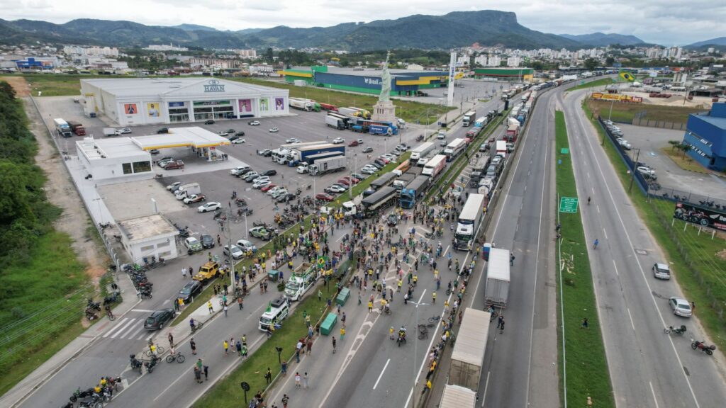 Aerial view showing supporters of President Jair Bolsonaro, largely truck drivers, blocking BR-101 highway in Palhoca, in the metropolitan region of Florianopolis, Santa Catarina State, Brazil, on October 31, 2022, as an apparent protest over Bolsonaro's defeat in the presidential run-off election. - The transition period got off to a tense start as truckers and demonstrators blocked several highways across Brazil on Monday in an apparent protest over the electoral defeat of Bolsonaro to leftist Luiz Inacio Lula da Silva, burning tyres and parking vehicles in the middle of the road to halt traffic. (Photo by Anderson COELHO / AFP) (Photo by ANDERSON COELHO/AFP via Getty Images)