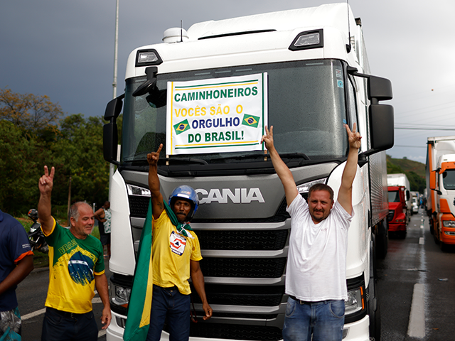 Truck drivers and supporters in favor of President Jair Bolsonaro display a banner that re