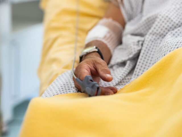 Close-up of a male patient's hand in a hospital bed with oximeter. Senior man admitte
