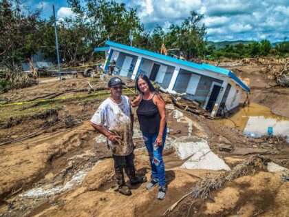 Leida Rodriguez and Javier Castellanos stand in front of their house that collapsed into a sinkhole after being flooded with water and mud during Hurricane Fiona at Villa Esperanza in Salinas, Puerto Rico. (Pedro Portal/El Nuevo Herald/Tribune News Service via Getty Images)