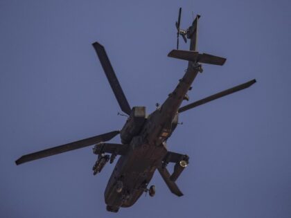 A U.S. Apache attack helicopter flies over a field near in the town of Tal Haddad in the c