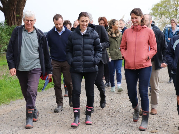 New Zealand Prime Minister Jacinda Ardern walks with the owners of Kaiwaiwai Dairies on a farm visit to announce the government's proposals to tackle climate change by reducing agricultural emissions and boosting exports on October 11, 2022 in Tauherenikau, near Wellington, New Zealand.  The New Zealand Government has unveiled a new proposal to reduce agricultural emissions to meet the country's 2030 methane reduction target. The proposed plans have also included many of the recommendations of the He Waka Eke Noa partnership of sector groups agriculture for pricing and reducing emissions.  (Photo by Lynn Grieveson/Getty Images)