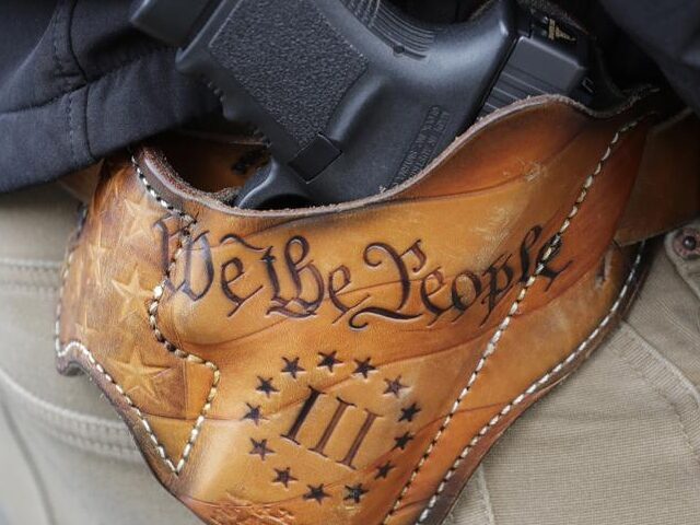 An attendee at a gun rights rally open-carries his gun in a holster that reads "We the Peo