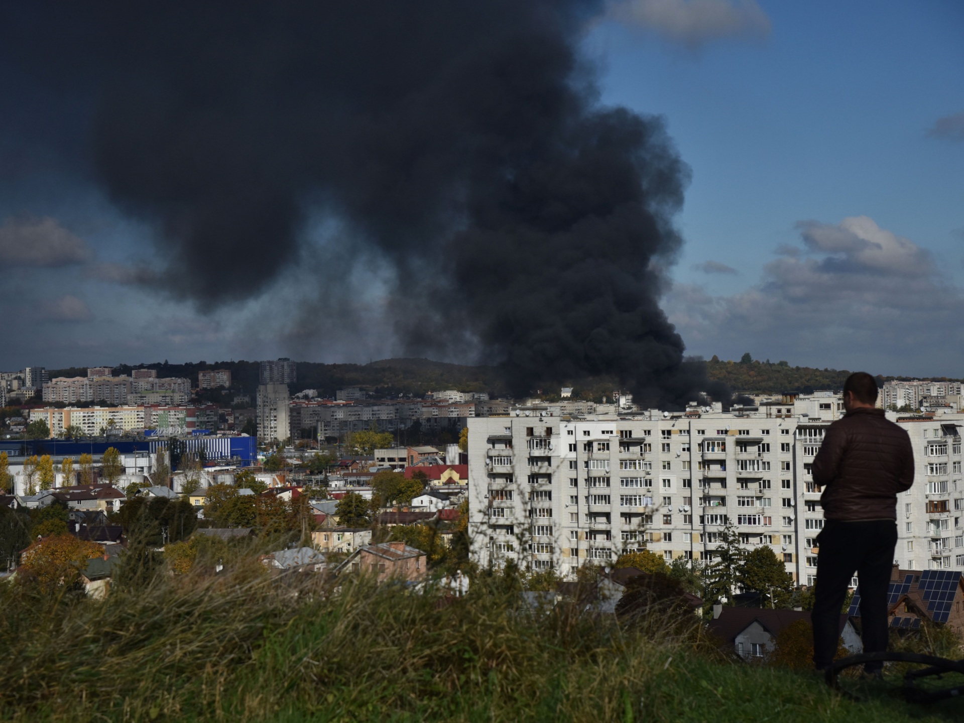 LVIV, UKRAINE - 2022/10/10: A man watches as smoke rises above the buildings after the Russian missile attack on the critical infrastructure of Lviv. Several powerful explosions were heard in Lviv and the region today. Russia launched 15 rockets in the Lviv region, some were shot down by air defense forces, the rest hit energy infrastructure facilities. Due to the rocket attack, Lviv was left without electricity, water and mobile communication. (Photo by Pavlo Palamarchuk/SOPA Images/LightRocket via Getty Images)