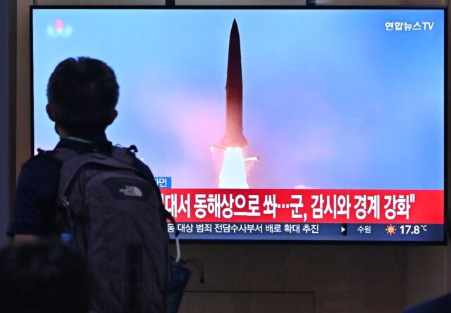 A man at a rail station in Seoul walks past a TV showing file footage of a North Korean mi