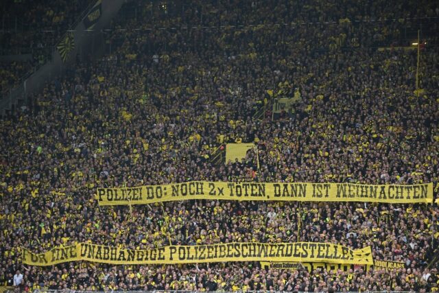 Dortmund fans hold a banner reading 'Police Do(rtmund) - killing two more times and then i