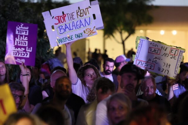 Israelis wave placards as they gather in the coastal city of Tel Aviv to demonstrate again