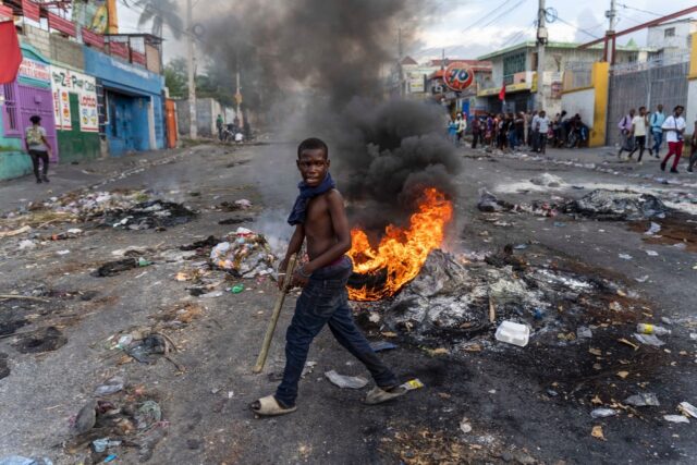 A mans walks past a burning barricade during a protest against Haitian Prime Minister Arie