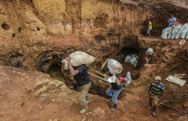 Miners carry sacks with rocks to be crushed in order to extract gold at a mine near Rosita