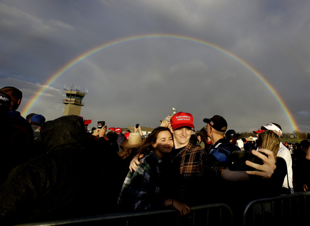 Supporters of former President Donald Trump take a selfie with a rainbow in the background after a brief rain storm during an election rally with Trump and candidates Doug Mastriano and Dr. Mehmet Oz in Latrobe, Pa. Saturday, Nov. 5, 2022. (AP Photo/Jacqueline Larma)