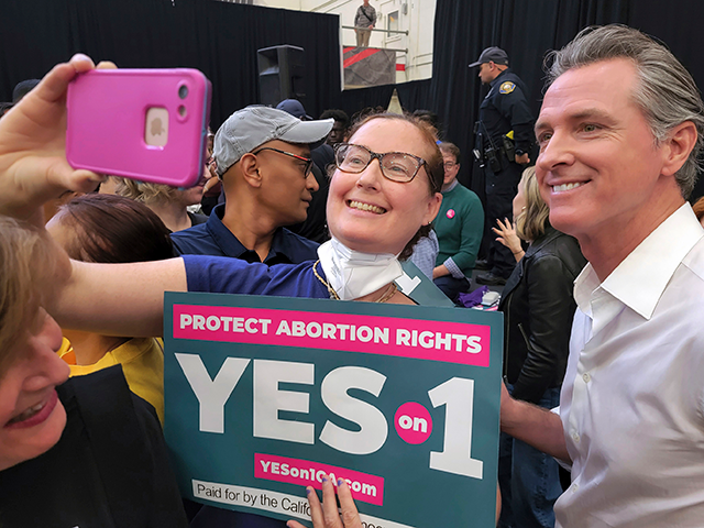 California Gov. Gavin Newsom, right, takes selfies with supporters at a turn out and vote