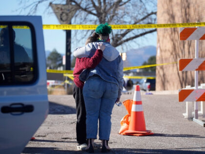 People console each other outside the police tape blocking a drive to Club Q, the site of