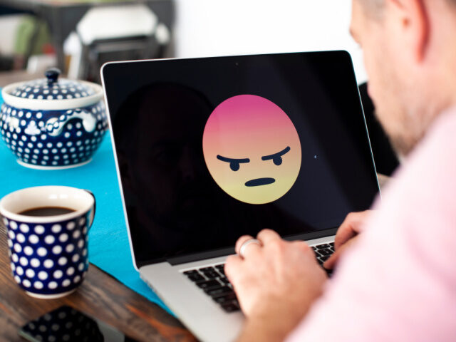 A laptop screen with an angry emoji face displayed is seen in this photo illustration on O