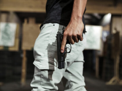 Close-up of man holding a pistol in an indoor shooting range - stock photoClose-up of man