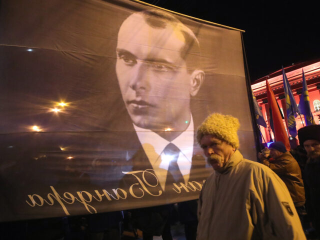 KYIV, UKRAINE - JANUARY 1, 2020 - An aged man stands on front of a banner featuring the OUN-B (Organisation of Ukrainian Nationalists) leader as the torchlight procession of honour, dignity and freedom held on the 111th birthday anniversary of Stepan Bandera takes off from Taras Shevchenko Park, Kyiv, capital …