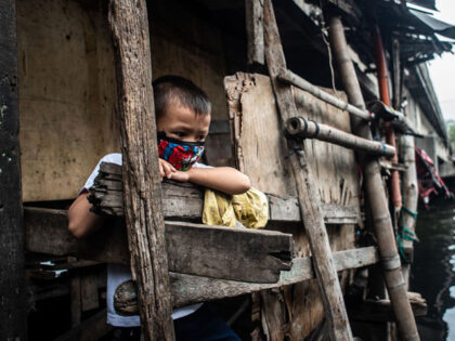 A boy wearing a face mask peeks out of a house located under a bridge in Manila, Philippines on August 2, 2020.(Photo by Lisa Marie David/NurPhoto via Getty Images)