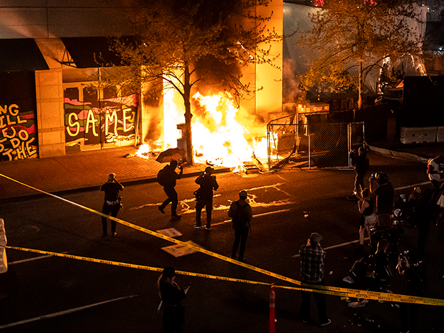 Protesters watch a structure fire, set following the police shooting of a homeless man on April 17, 2021 in Portland, Oregon. The shooting comes amid heightened tensions between police and activists as the country awaits a verdict in the trial of Derek Chauvin. (Photo by Nathan Howard/Getty Images)