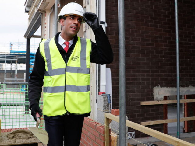 Britain's Chancellor of the Exchequer Rishi Sunak, wearing a hard hat and a hi-vis ja