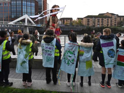 Little Amal, a giant puppet depicting a Syrian refugee girl, is greeted by local school children, on the banks of the River Clyde, in Glasgow on November 10, 2021, during the COP26 UN Climate Change Conference. - A draft text at the COP26 climate summit urged countries on Wednesday to …