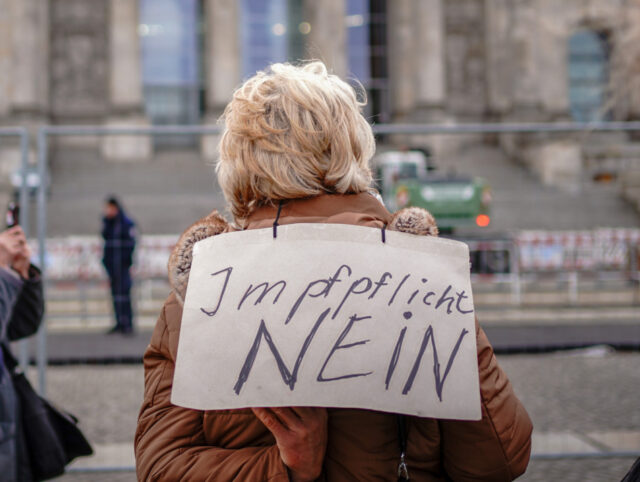 07 April 2022, Berlin: Demonstrators protest against compulsory vaccination with placards in front of the Reichstag building this morning. The Bundestag votes in its session on a mandatory vaccination against the coronavirus. Photo: Kay Nietfeld/dpa (Photo by Kay Nietfeld/picture alliance via Getty Images)