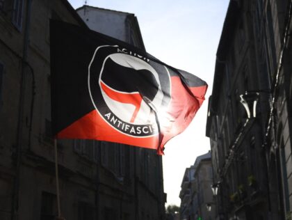 A protester waves the anti-fascist movement flag "Action antifasciste" during a rally against the French far-right party Rassemblement National (RN) presidential candidate's visit in Avignon on April 14, 2022. - French far-right party Rassemblement National (RN) presidential candidate faces the incumbent president in a run-off vote on April 24, 2022. …