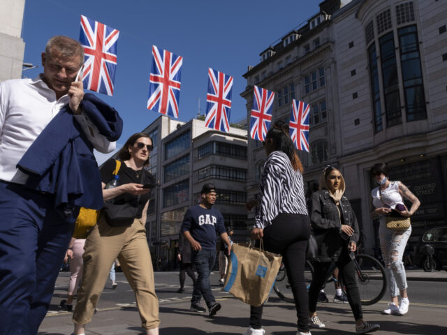 Union Flags hanging high above Oxford Street as shoppers, visitors and Londoners pass by i