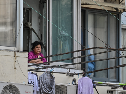 A resident looks out from her window during a Covid-19 coronavirus lockdown in the Jing'an district of Shanghai on May 25, 2022. (Photo by Hector RETAMAL / AFP) (Photo by HECTOR RETAMAL/AFP via Getty Images)
