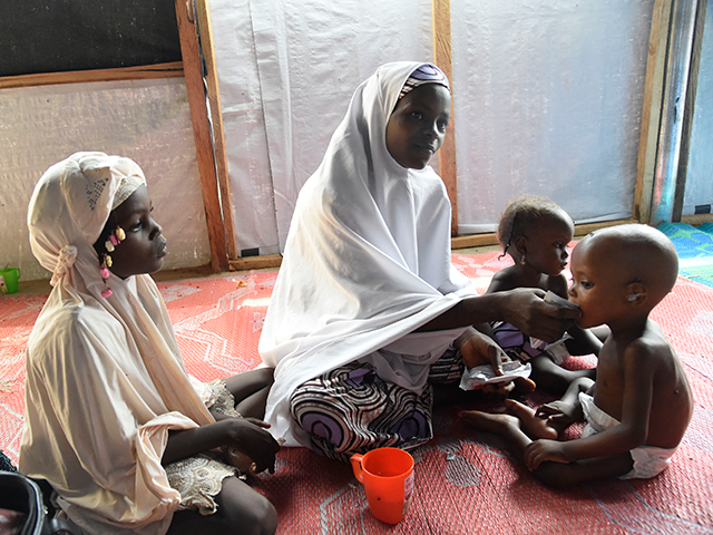 A mother feeds child suffering malnutrition in a clinic set up by health authorities with