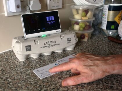 An energy customer examines the smart meter in her flat on the south London estate where she lives, on August 25, 2022. - Increasingly cash-strapped Britons learn Friday, August 26, how much their electricity and gas bills will rise in October, as the regulator unveils its latest energy price cap …