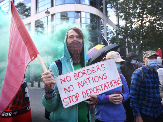 LONDON, ENGLAND - SEPTEMBER 24: A counter demonstration forms near the Home Office with a protester holding a sign saying 'No Borders No Nations Stop Deportations as police contain them so the pro and anti immigration protest groups are unable to meet on September 24, 2022 in London, England. Protesters …